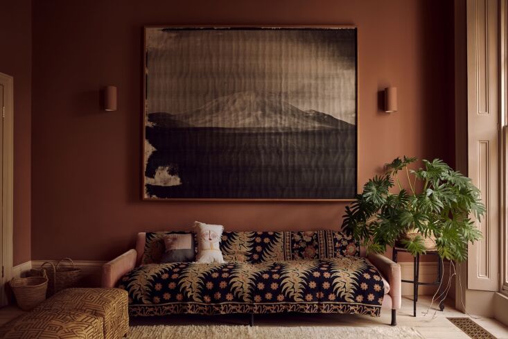 A living room with Marrakesh pink walls, original wooden floors, and vintage window shutters.
