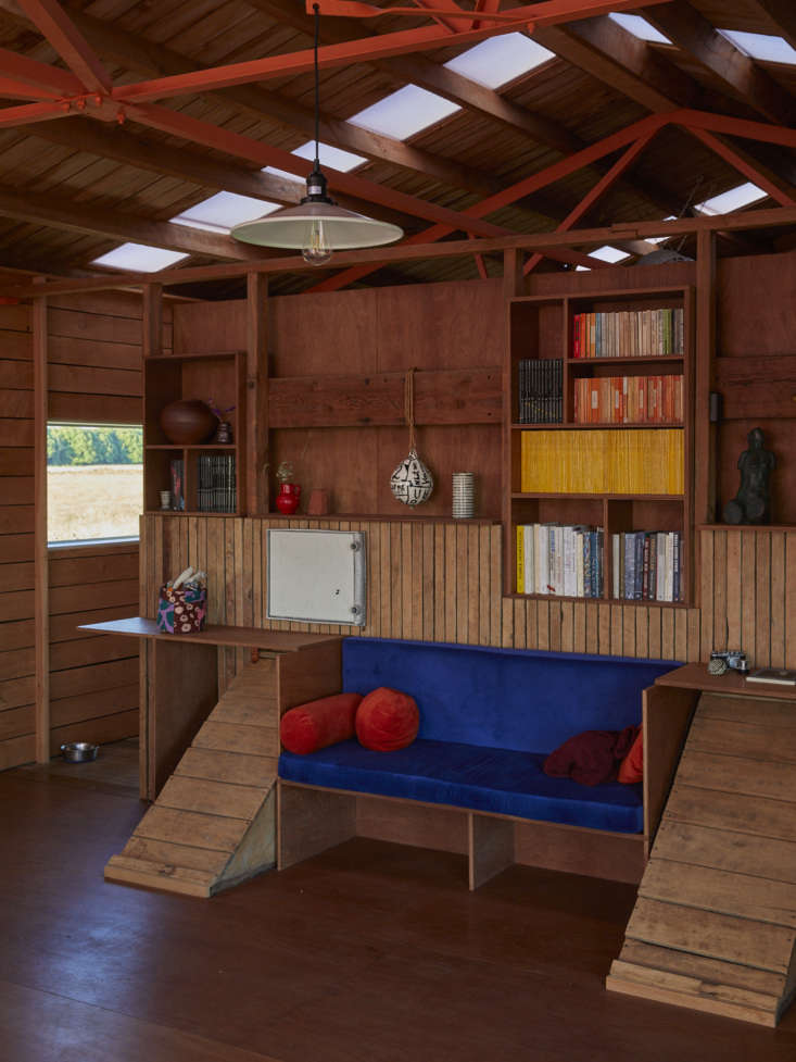 Close-up of wooden bookshelves and a bench integrated into the original shed timber framing and sheep chutes.