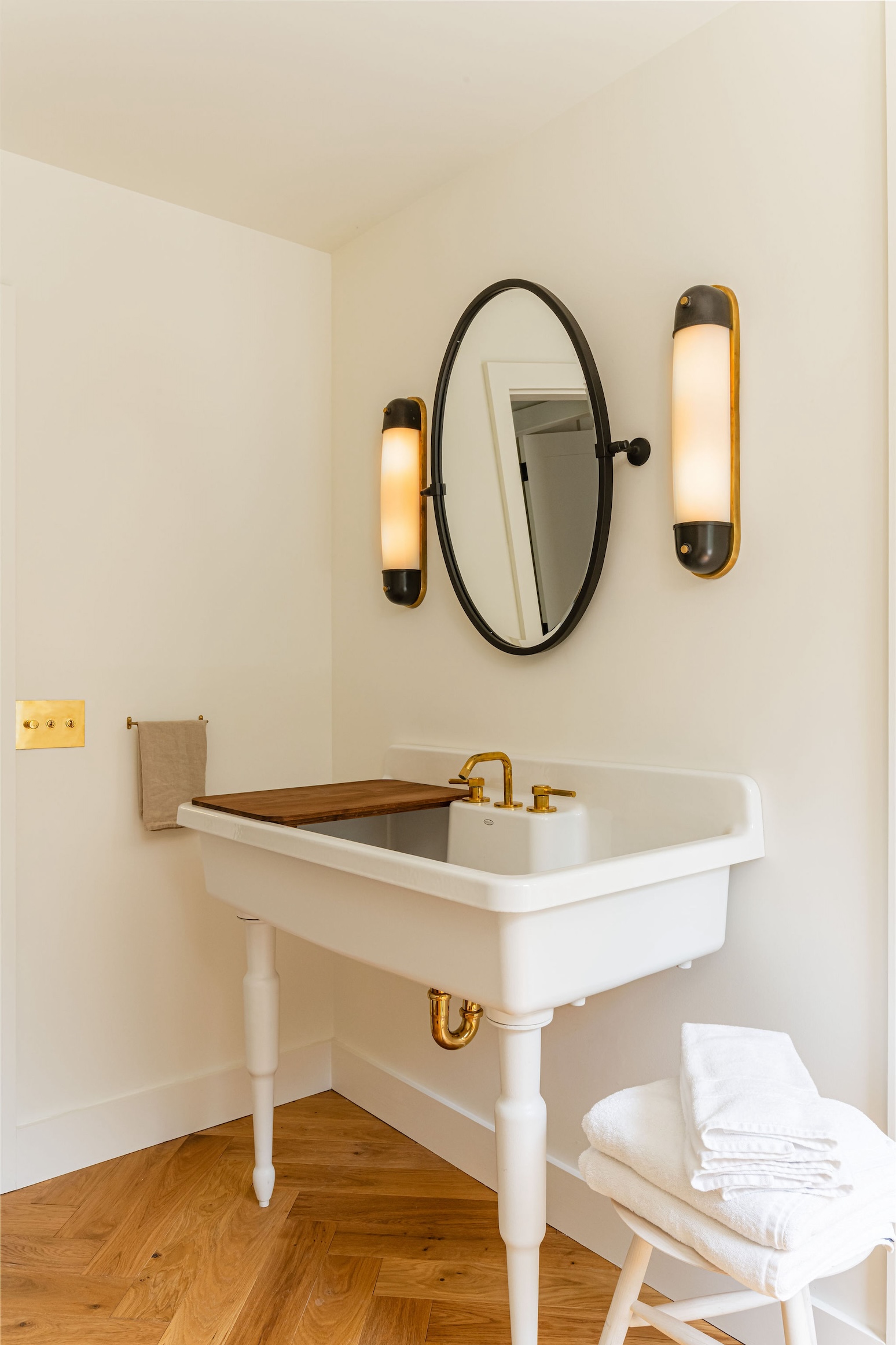 A bathroom featuring a Kohler Farmstead sink with brass legs and a brass Watermark faucet.