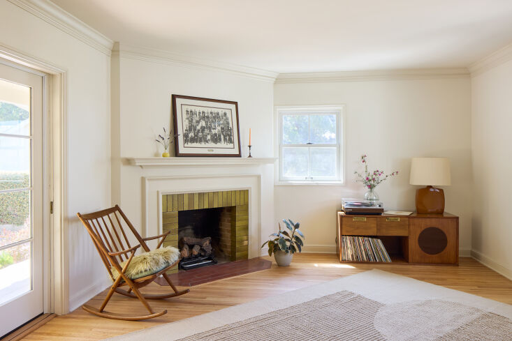 A living room featuring original oak floors and a green tiled fireplace surround.