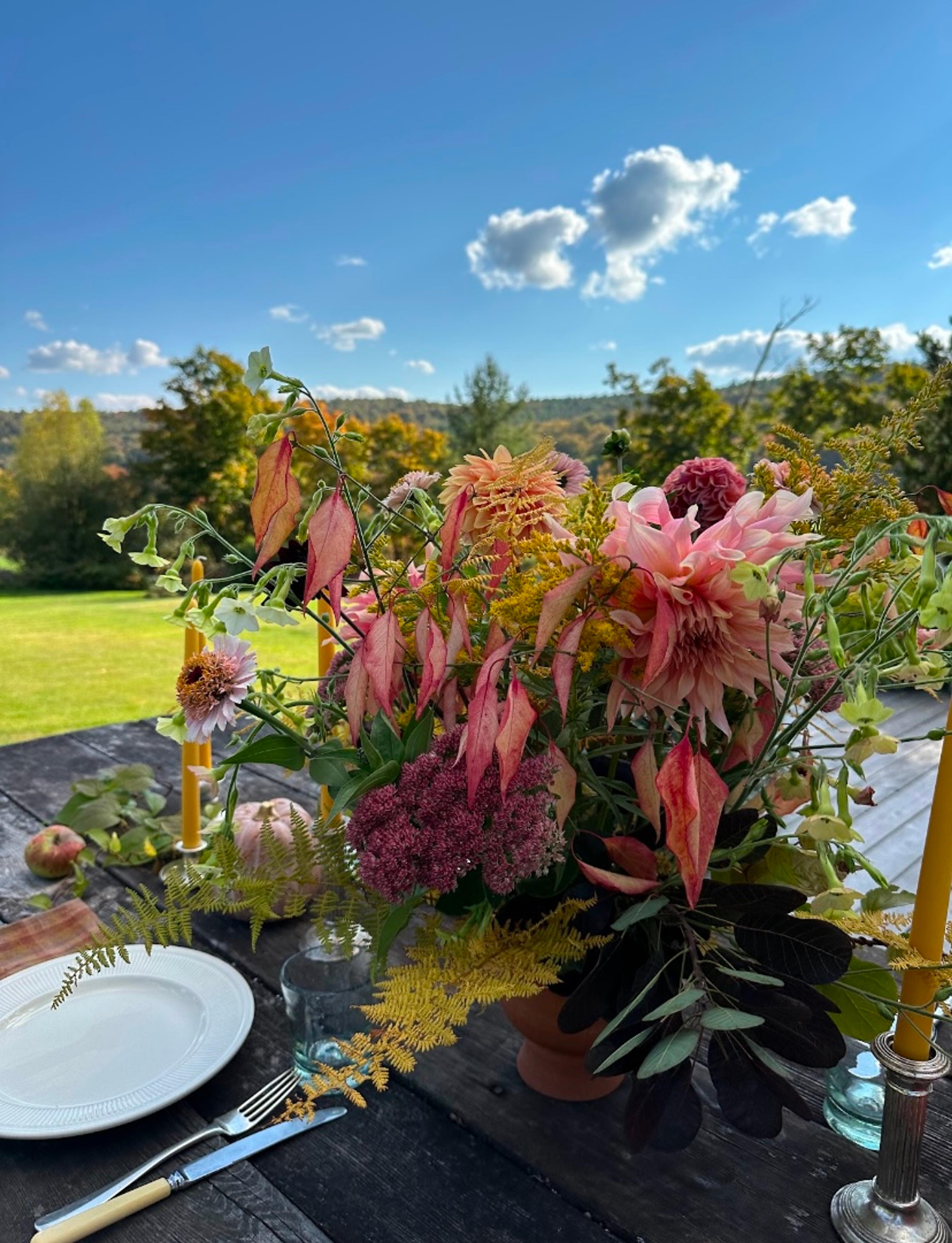 Large floral centerpiece with greenery draping over the edge of a decorated tablescape.