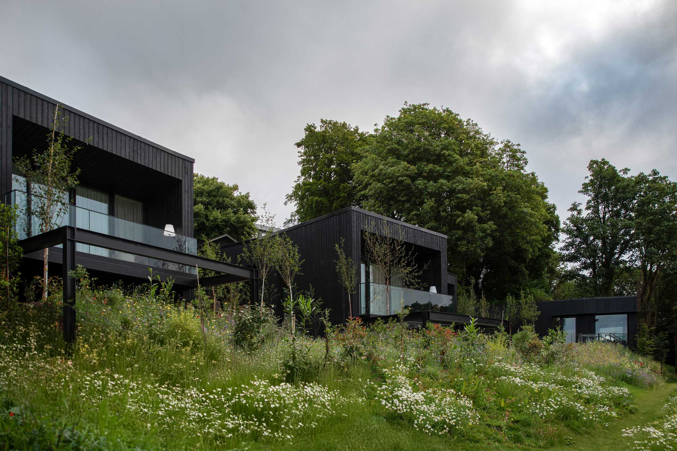 A wide exterior shot of the modern Woodland Suites cantilevered over a forested slope.