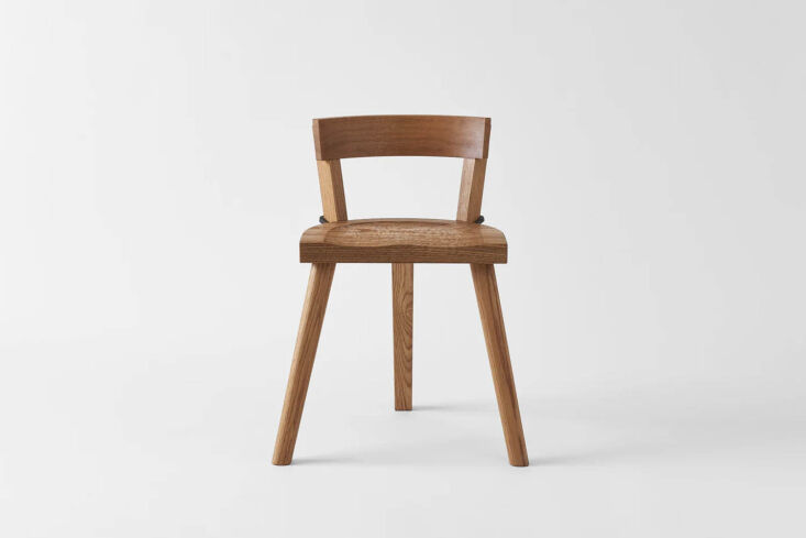 The Marolles Chair featuring a tripod-style wooden seat and iron backrest support.