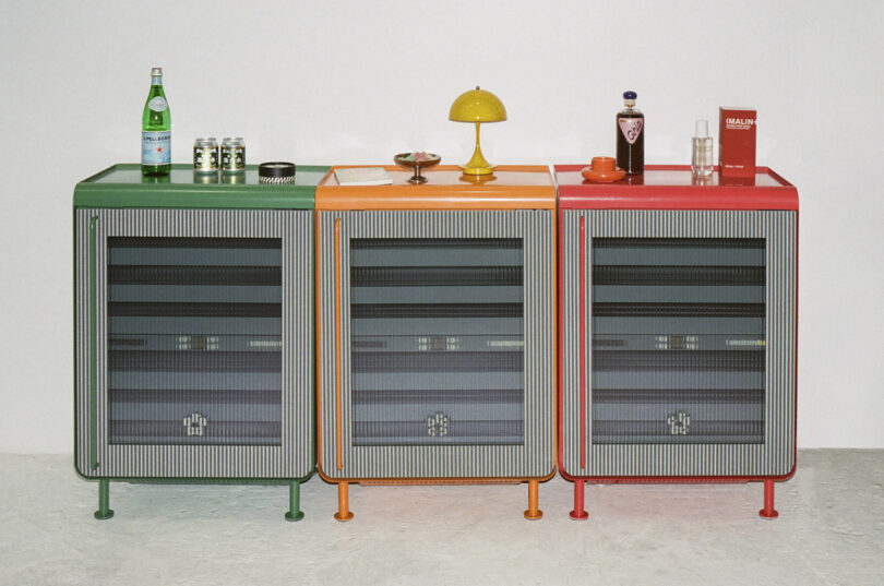 Three colorful Rocco fridges in green, orange, and red lined up against a white wall.