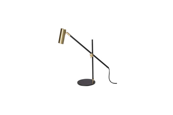 A black brass Rubn Lektor desk lamp on a dark surface.