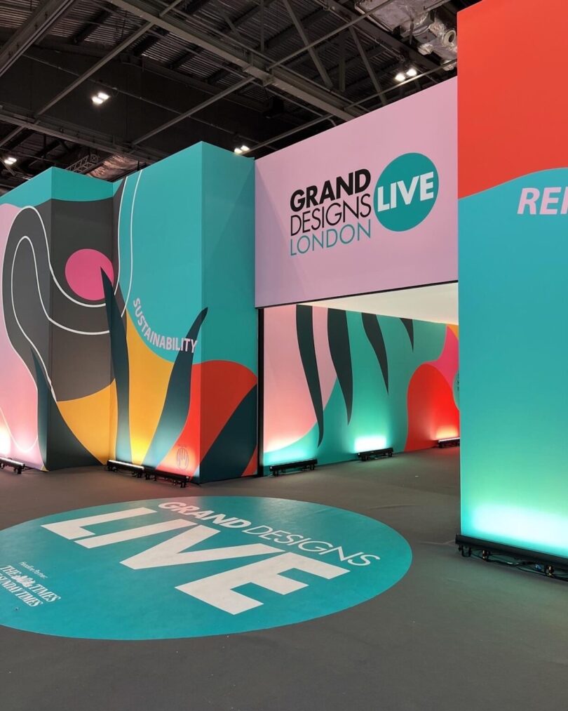 Entrance to the Grand Designs Live London event with 'Sustainability' signage and colorful murals.