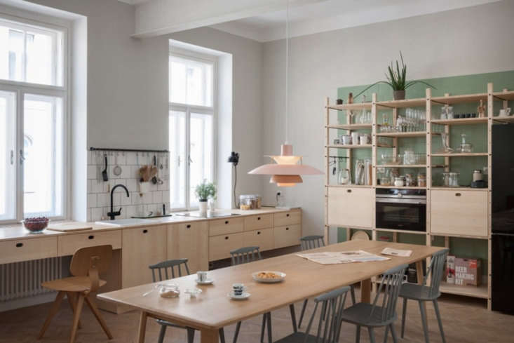 Custom ash wood kitchen cabinets and shelving in a minimalist, open-plan apartment.