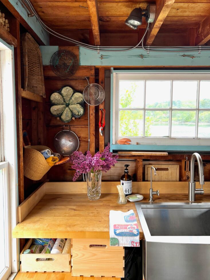 Industrial stainless steel sink and wooden toolbox drawers in a renovated kitchen.
