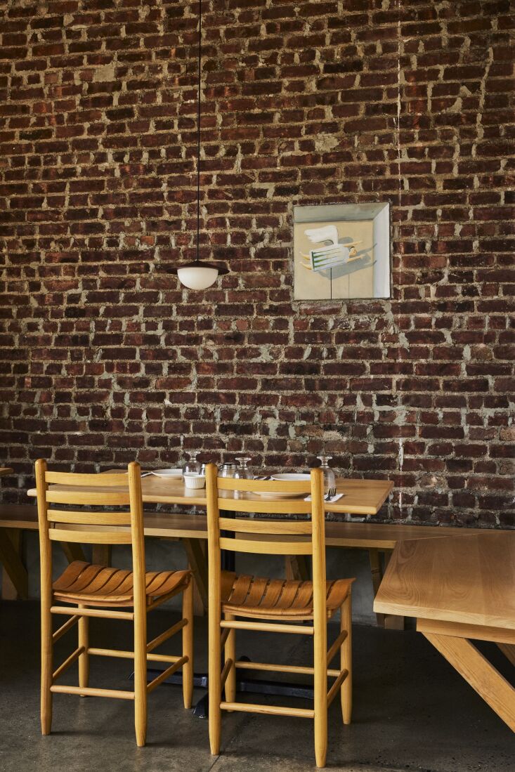 Small hand-painted murals on an exposed, repointed brick wall inside the restaurant.