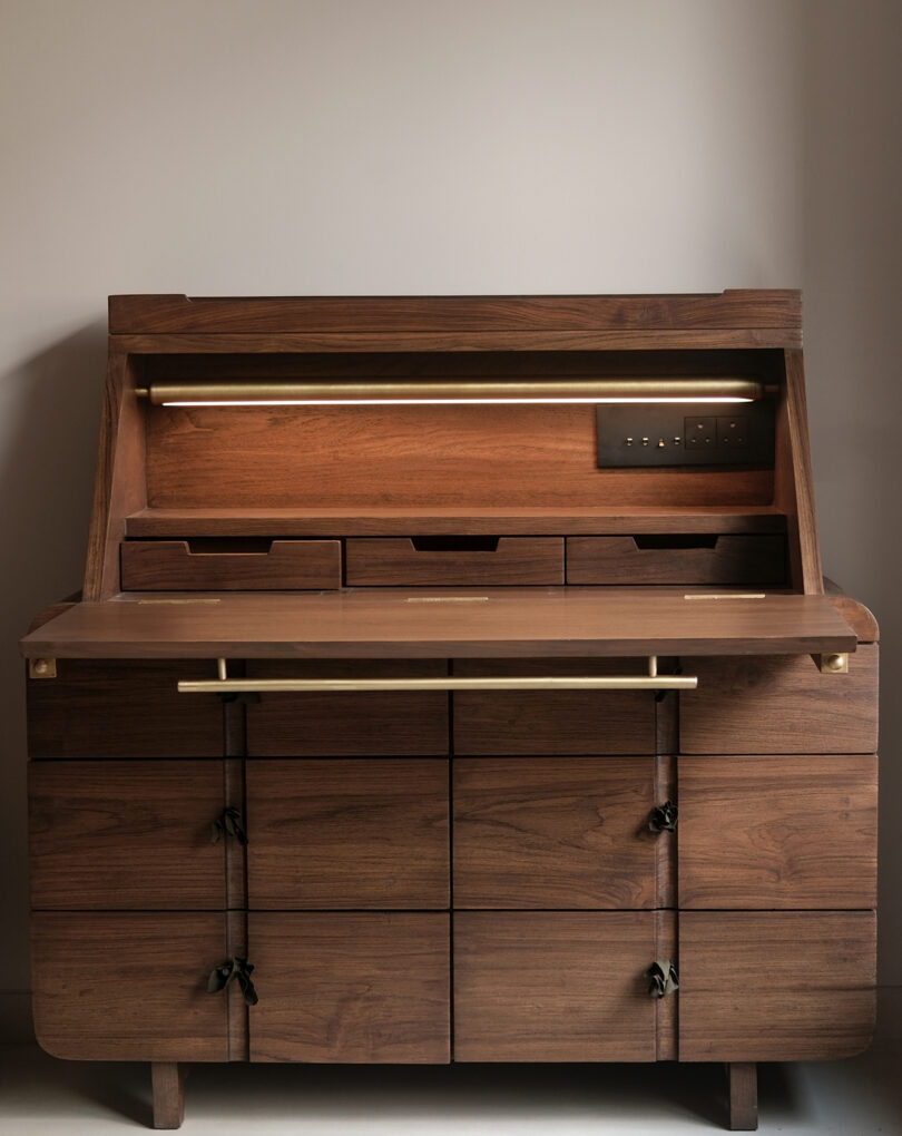 The interior of a wooden desk featuring a pull-down surface, built-in lighting, and organized compartments.