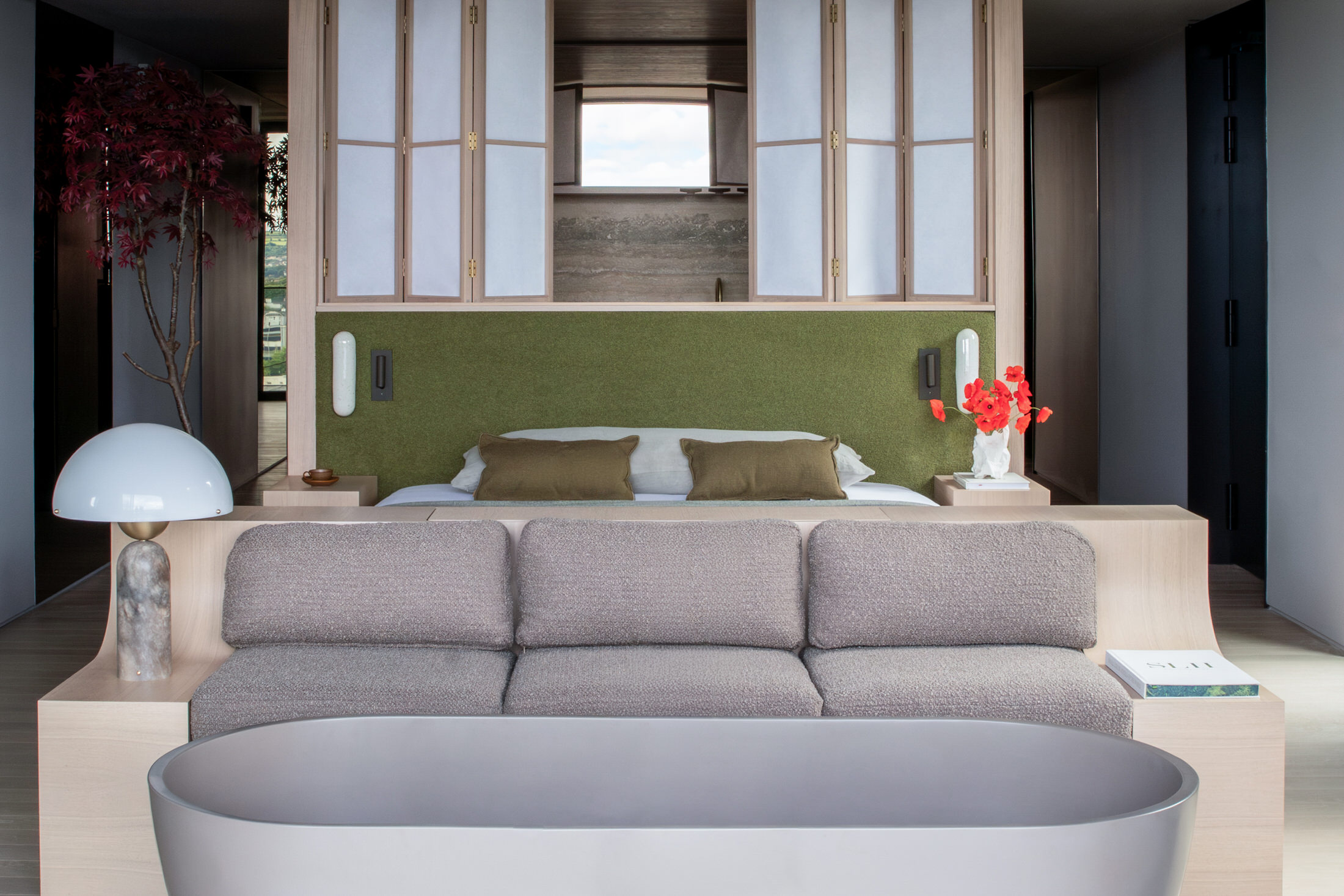 Interior of a suite featuring a bed positioned to face a large window overlooking the treetops.
