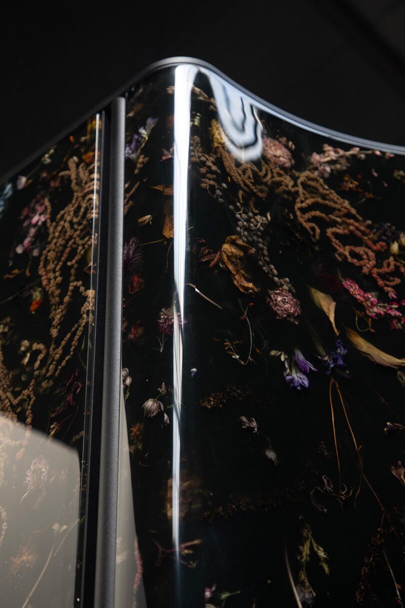 A macro shot of dried flowers and organic matter suspended within a glossy, translucent resin surface.