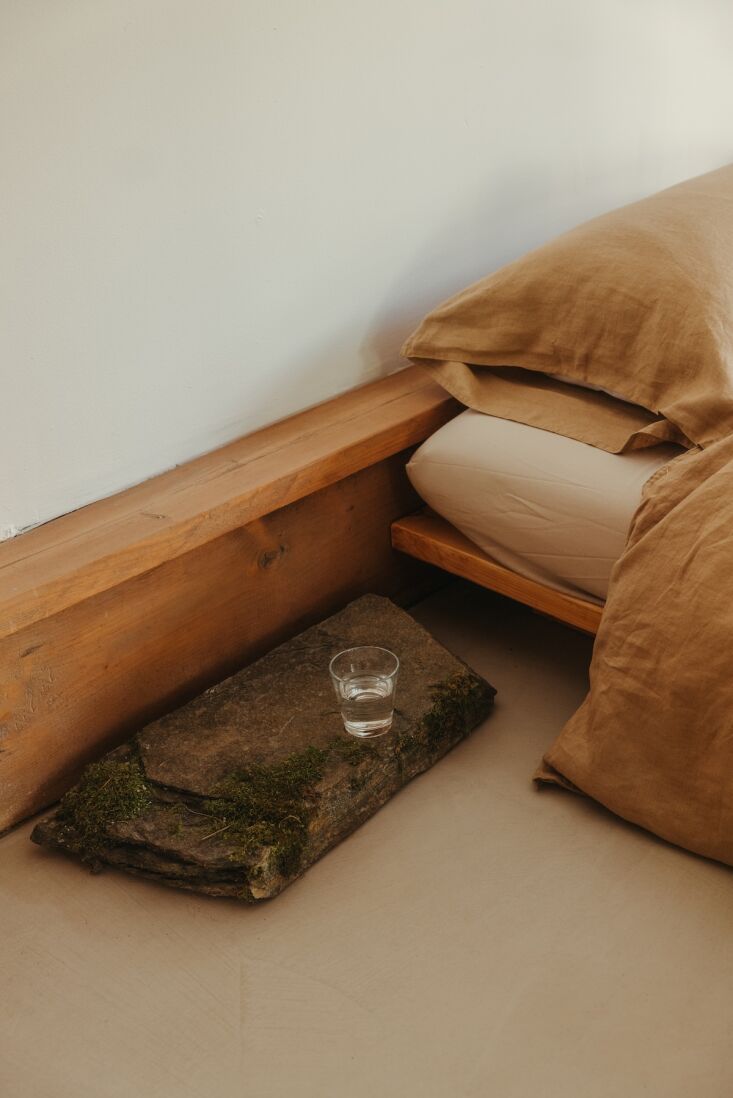 A large stone slab used as a bedside table with natural moss growing on its surface.