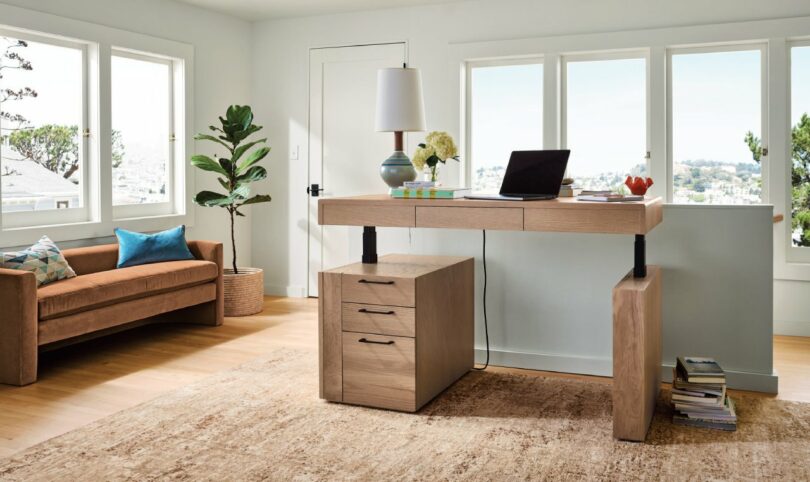 A modern home office featuring the Lincoln desk in a raised standing position near a large window.