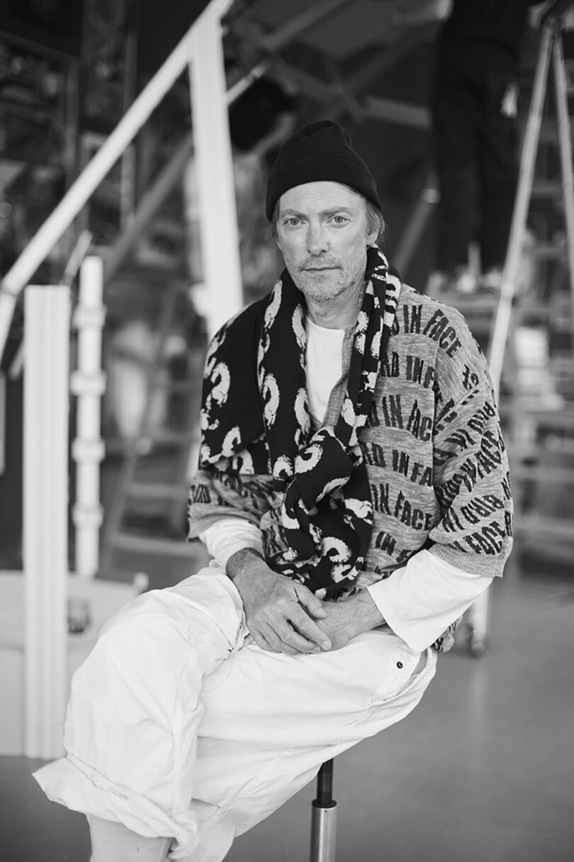 Portrait of designer Henrik Vibskov wearing a beanie and patterned scarf.