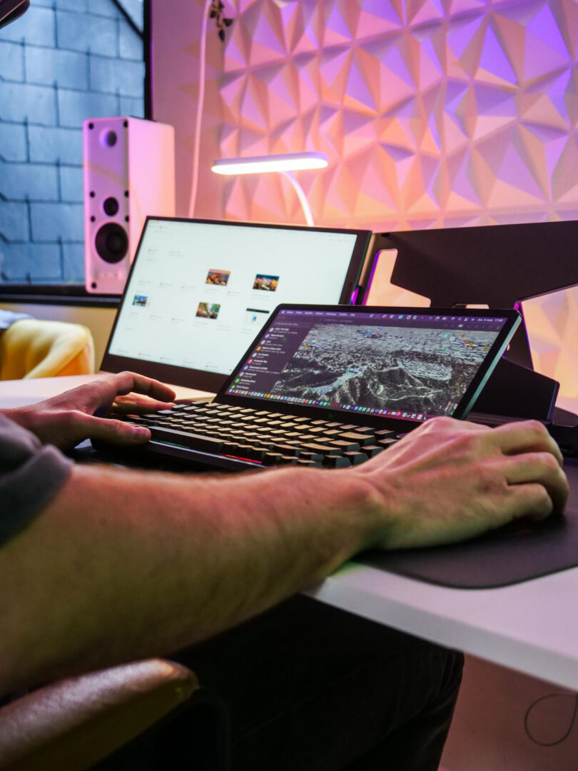 A person using a traditional dual-monitor setup with a separate keyboard and mouse.