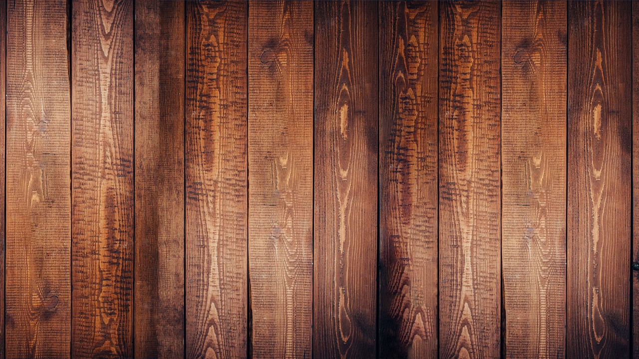 Close-up of polished teak wood grain showing natural oil patterns.