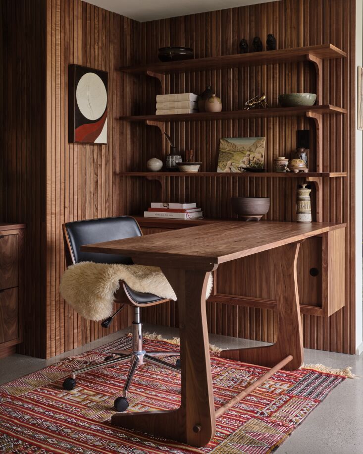 Custom walnut desk in a mid-century home office overlooking a backyard pool, featuring a leather chair.