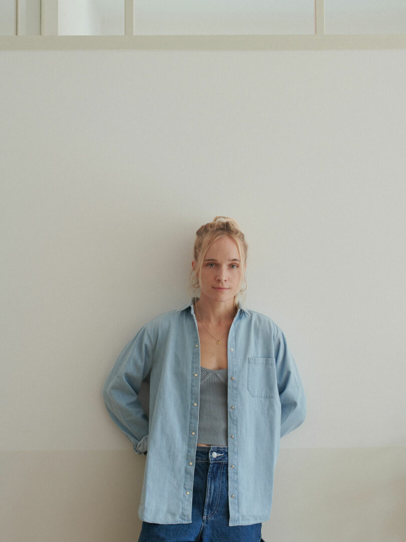 Portrait of designer Sarolta Huttl standing against a light-colored wall.
