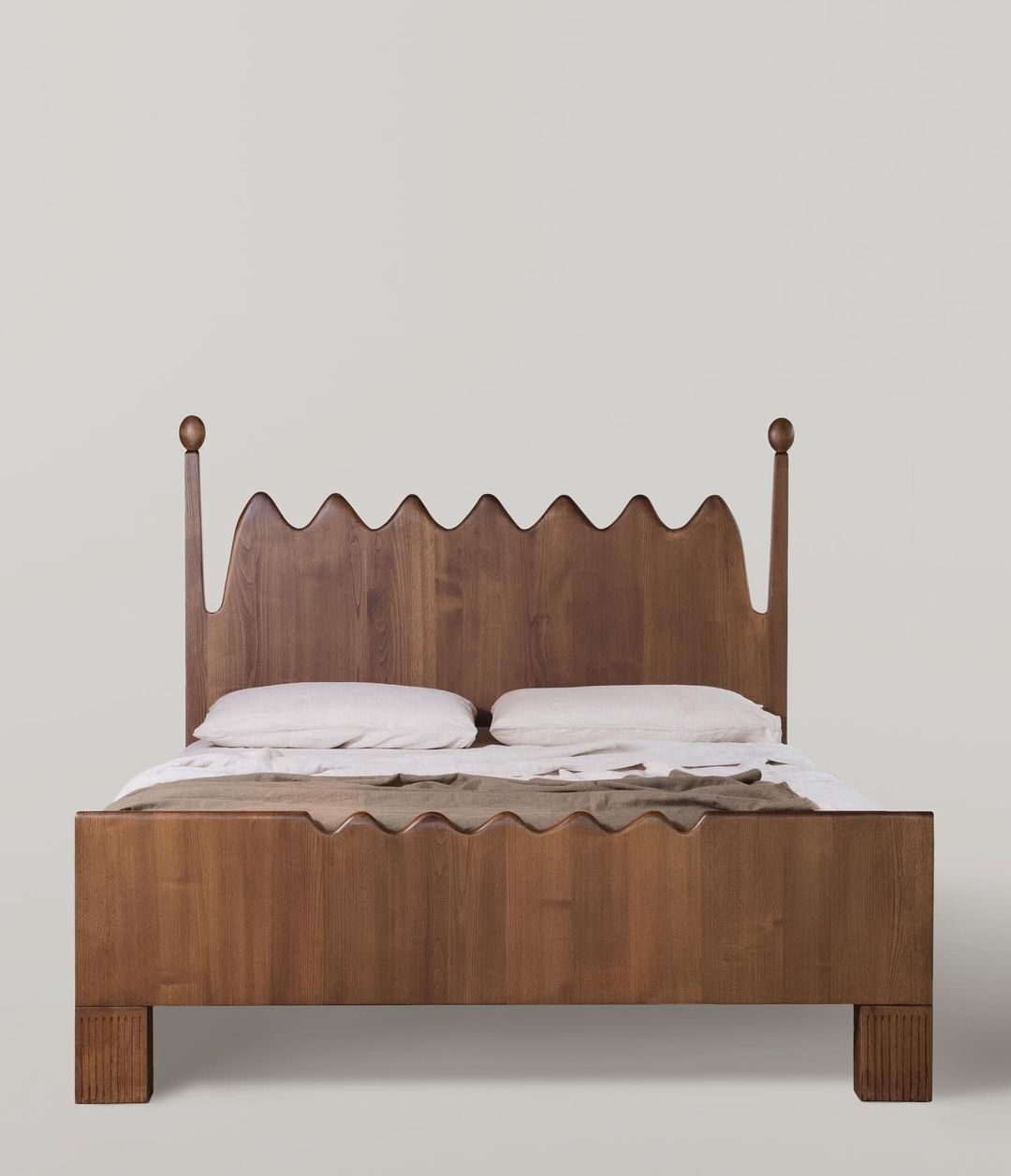 A wavy-edged chestnut wooden bed frame in a rustic, minimalist room.