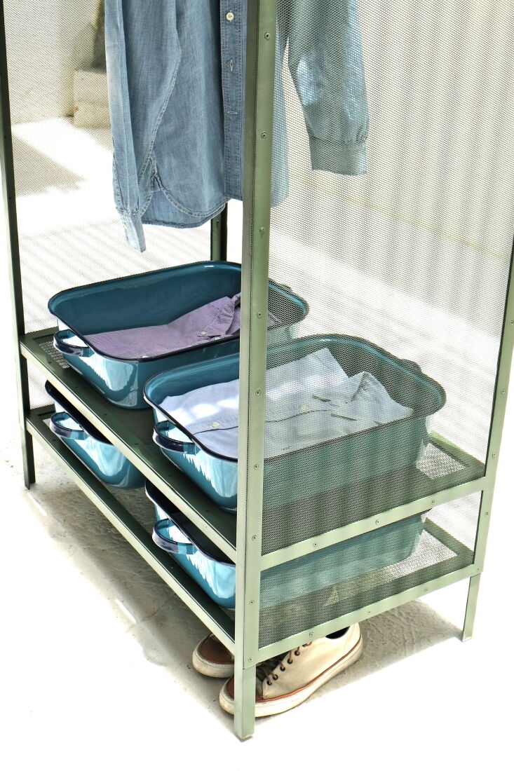 Blue and white enamelware trays holding perfectly folded white shirts on a closet shelf.