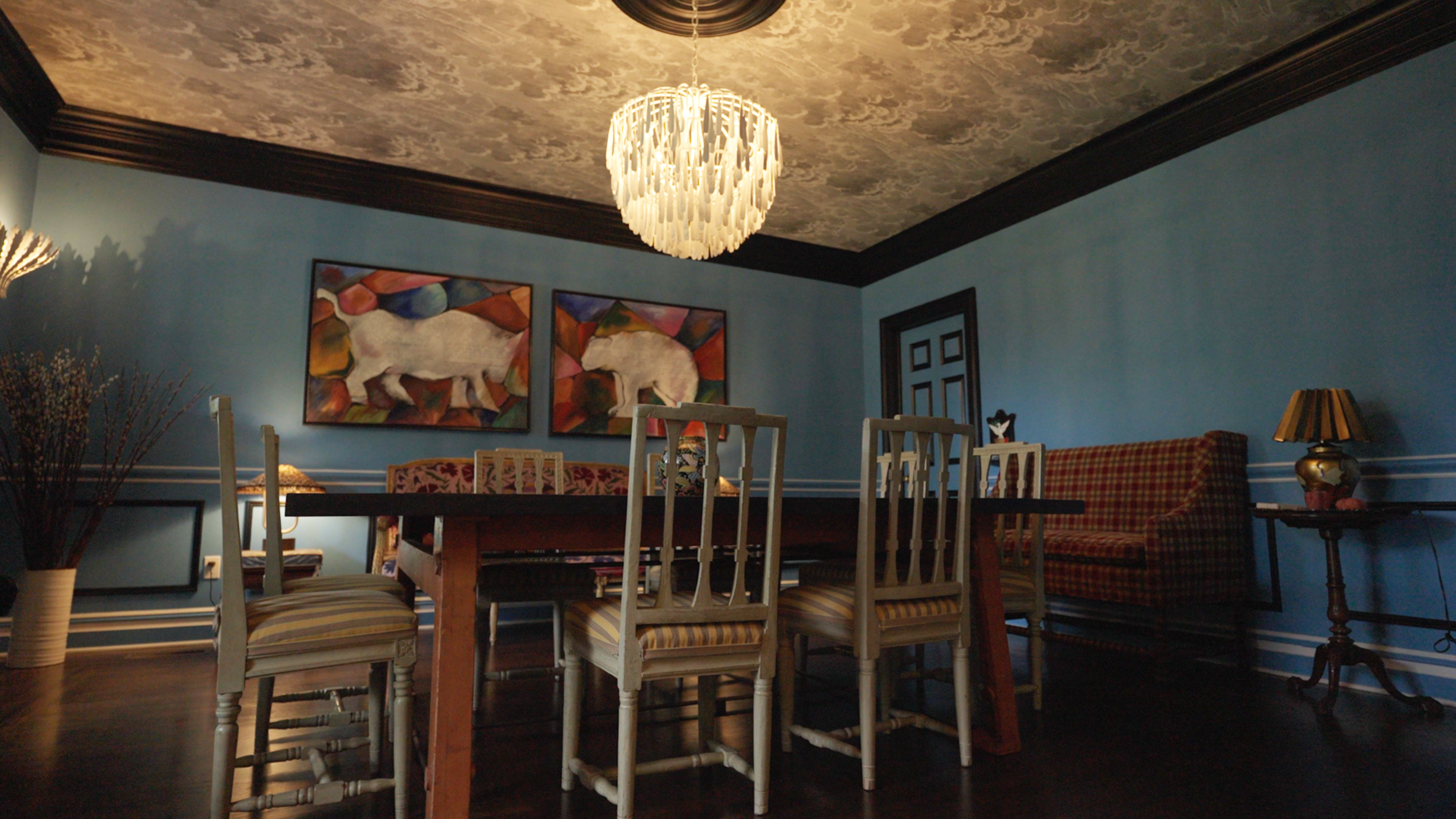 A dining area with clashing wallpaper and upholstery held together by a consistent color palette.
