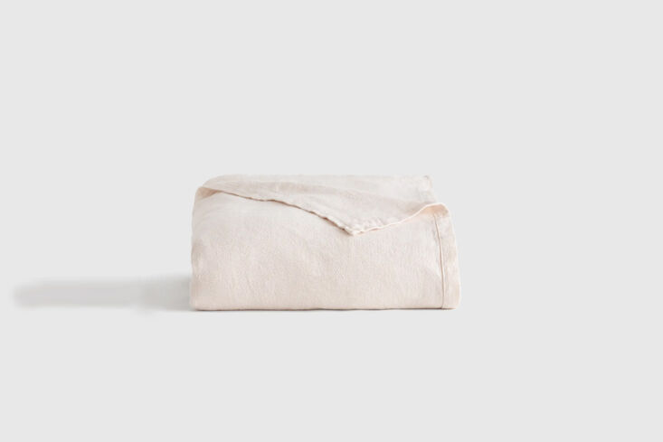 A neutral oat-colored vintage wash bed cover draped over blue-toned bedding.