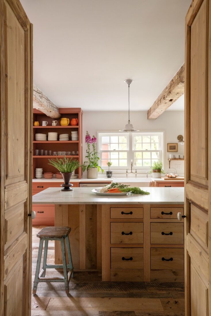 A tall, aged English pine door set within a custom frame in a room with lime-washed walls.
