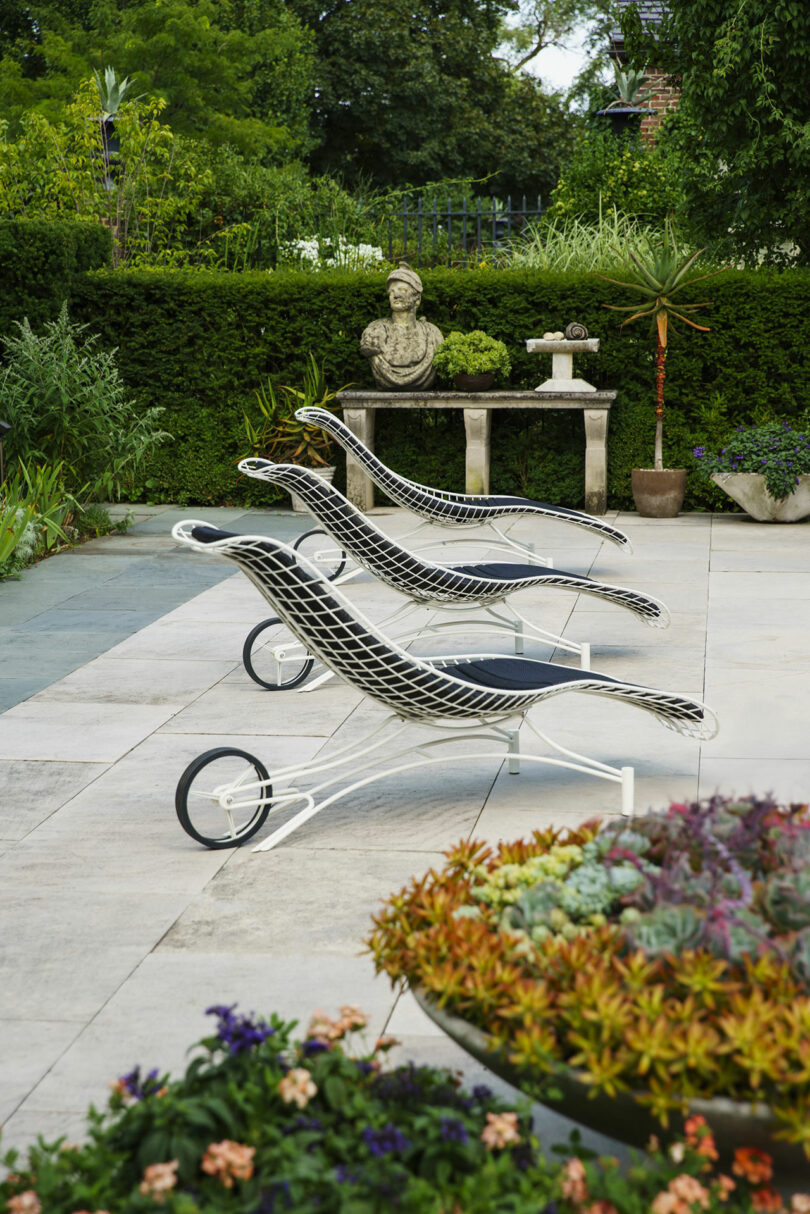 Modern black and white lounge chairs arranged on a patio next to a table holding a classic bust sculpture.