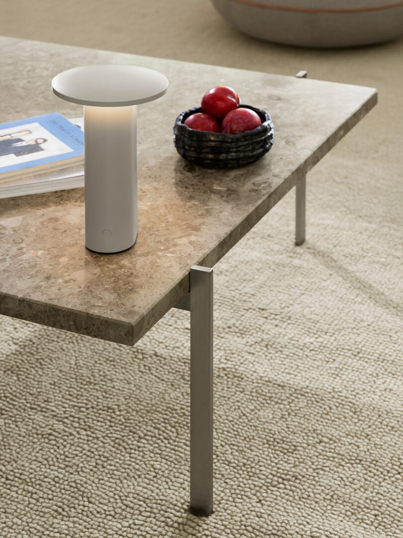 A white Solae lamp on a marble coffee table in a modern living room.