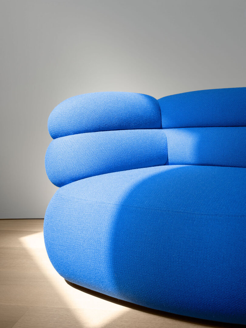 Close-up of the blue Biboni sofa's layered cushions against a neutral gray wall.
