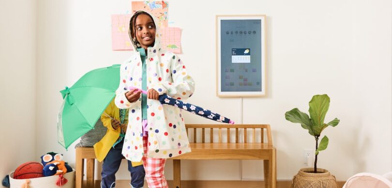 A bright room featuring a wall-mounted digital calendar near children and a wooden bench.