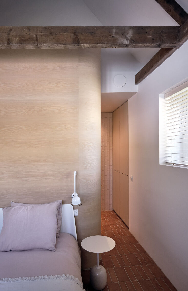 A bedroom featuring a curved ash veneer wall and modern minimalist lighting.
