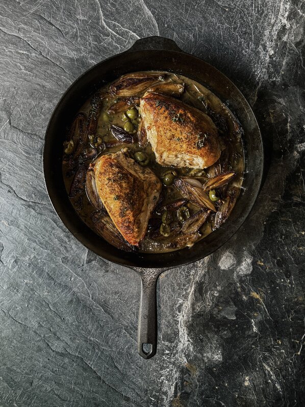 Plated pan-roasted chicken with crispy skin served with seasonal vegetables.