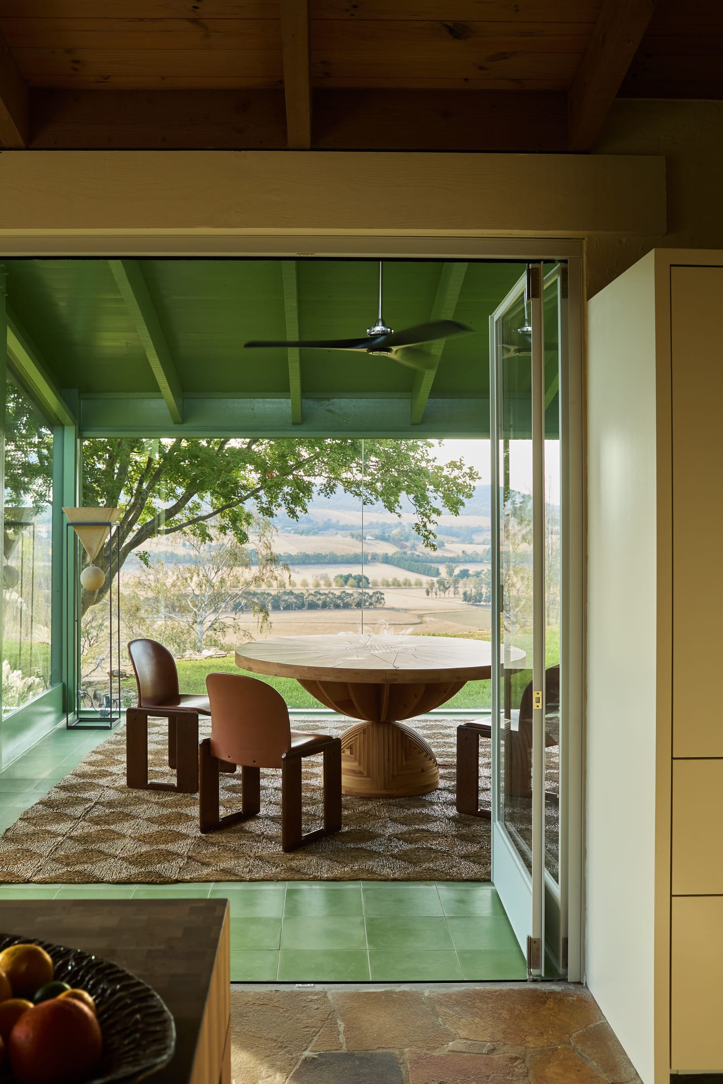 A floor-to-ceiling window overlooking a lush green landscape.