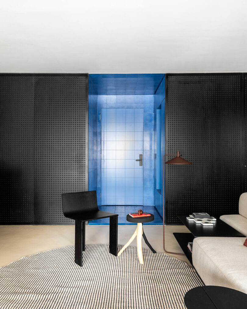 Blue-tiled doorway framed by black perforated metal panels next to a modern interior setting.