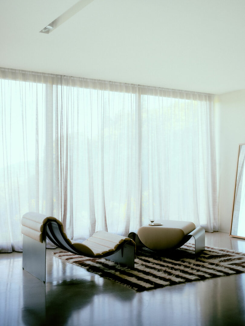 Modern minimalist lounge chair and matching ottoman on a zebra-patterned rug in a luxurious interior.
