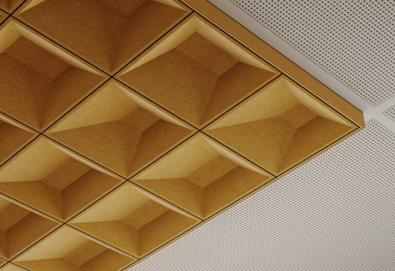 Close-up of golden-brown recessed geometric acoustic ceiling panels.