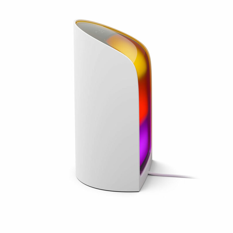 The Philips Hue Play device standing vertically, glowing with a gradient of orange, yellow, and purple light.