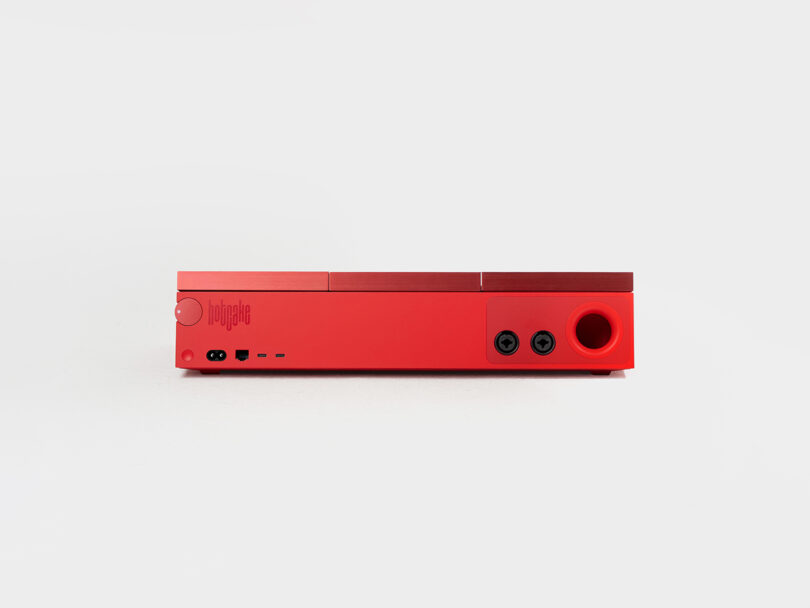 Close-up of a red electronic device featuring multiple audio jacks and ports.