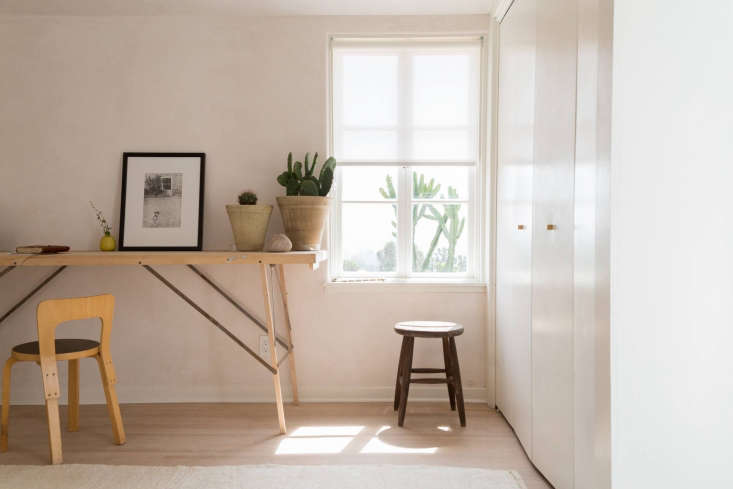 A slim vintage wallpaper table used as a writing desk in a minimalist room.