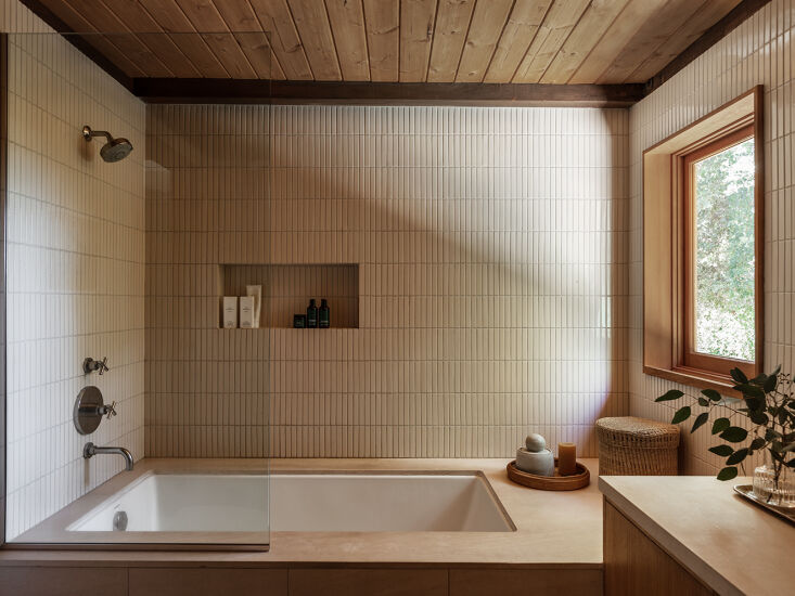Interior shot showing warm wood paneling meeting light-colored natural stone and earthy floor tiles.