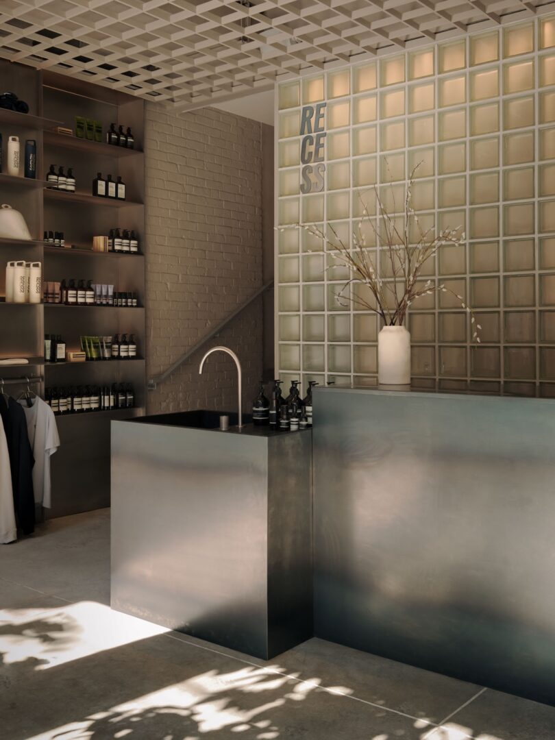 Minimalist reception area at RECESS featuring glass bricks and a metal service counter.