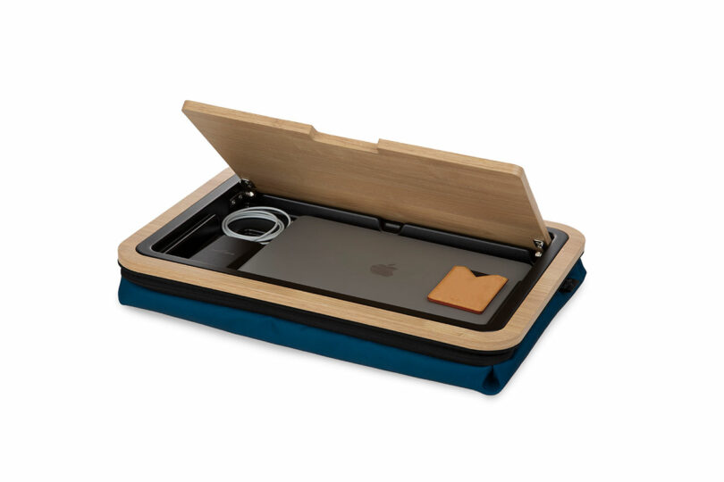 The Arlo Skye lap desk with its lid open, revealing a laptop and charger stored inside the hidden compartment.