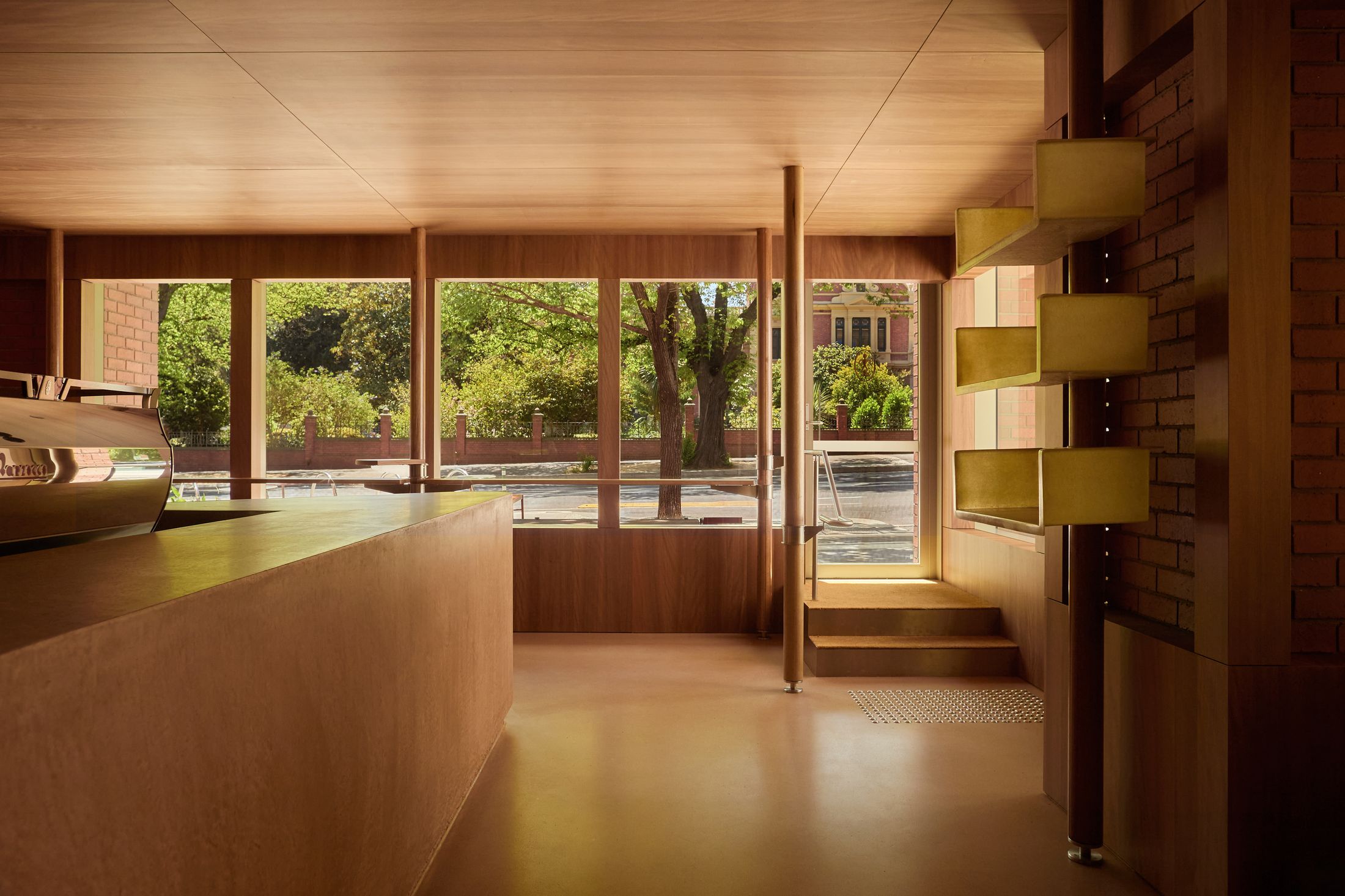 Wide perspective of the L-shaped interior at Standing Room showing timber-clad surfaces and open space.