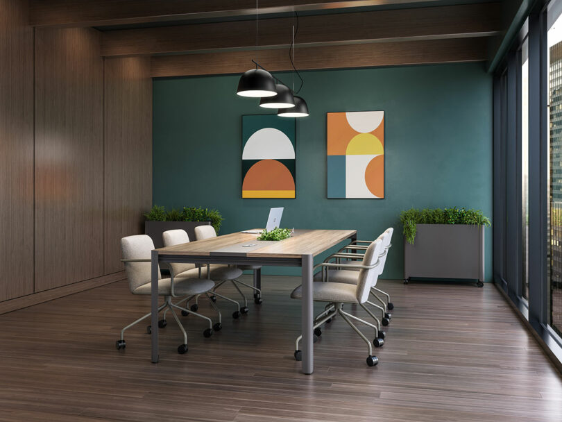 A modern conference room with a large wooden table, ergonomic chairs, and large windows surrounded by indoor plants.