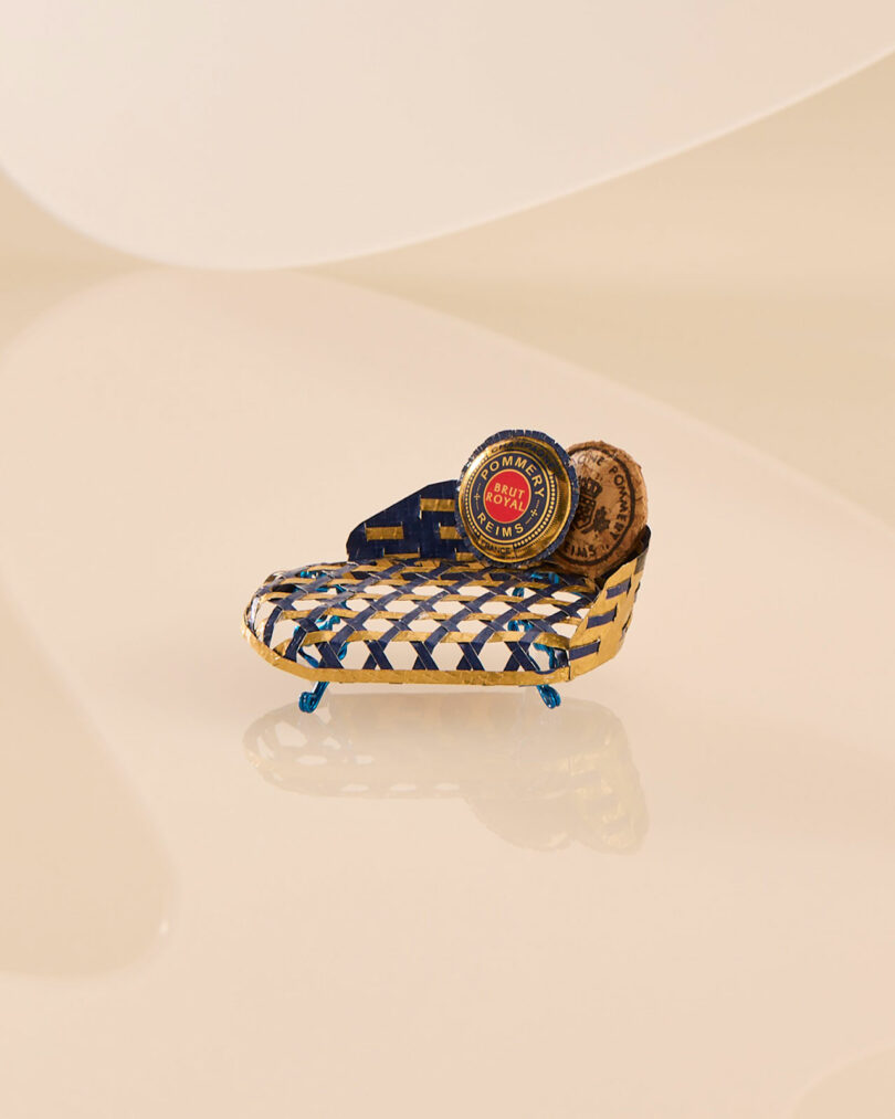 An ornate blue and gold miniature chaise longue with a circular emblem.
