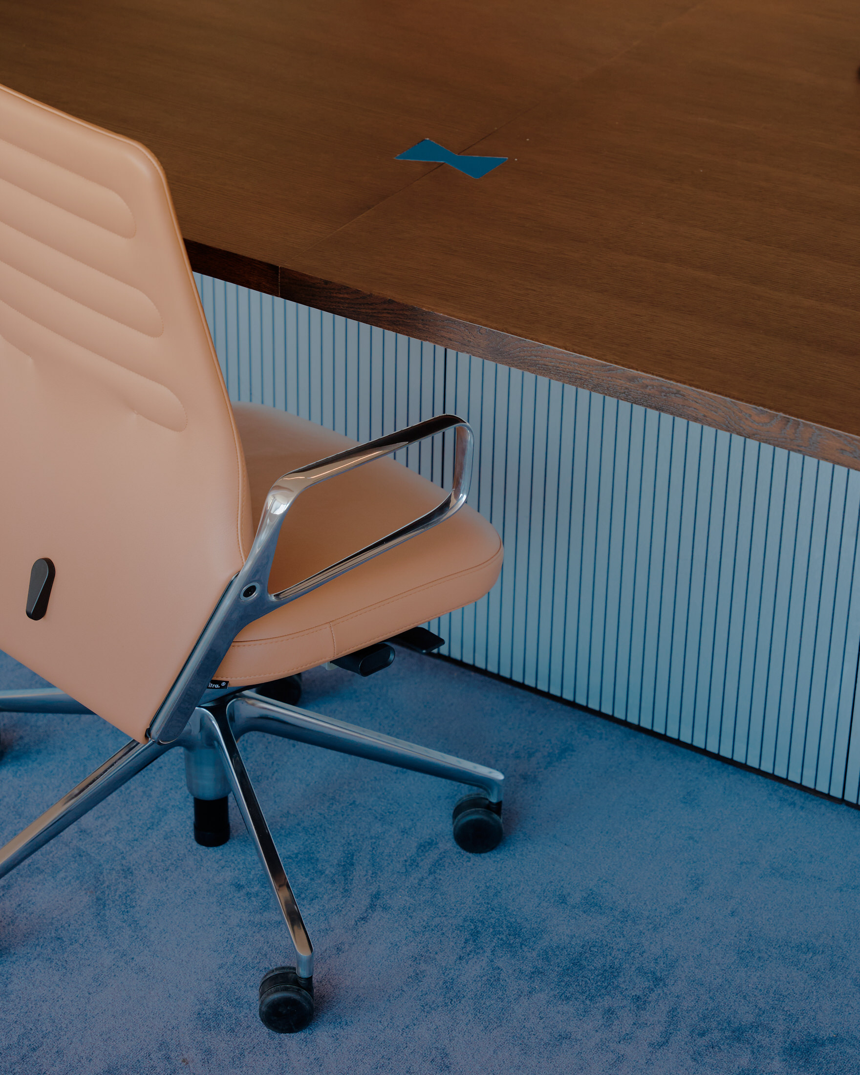 Interior shot featuring purple-blue carpets and tan leather seating in a communal office space.