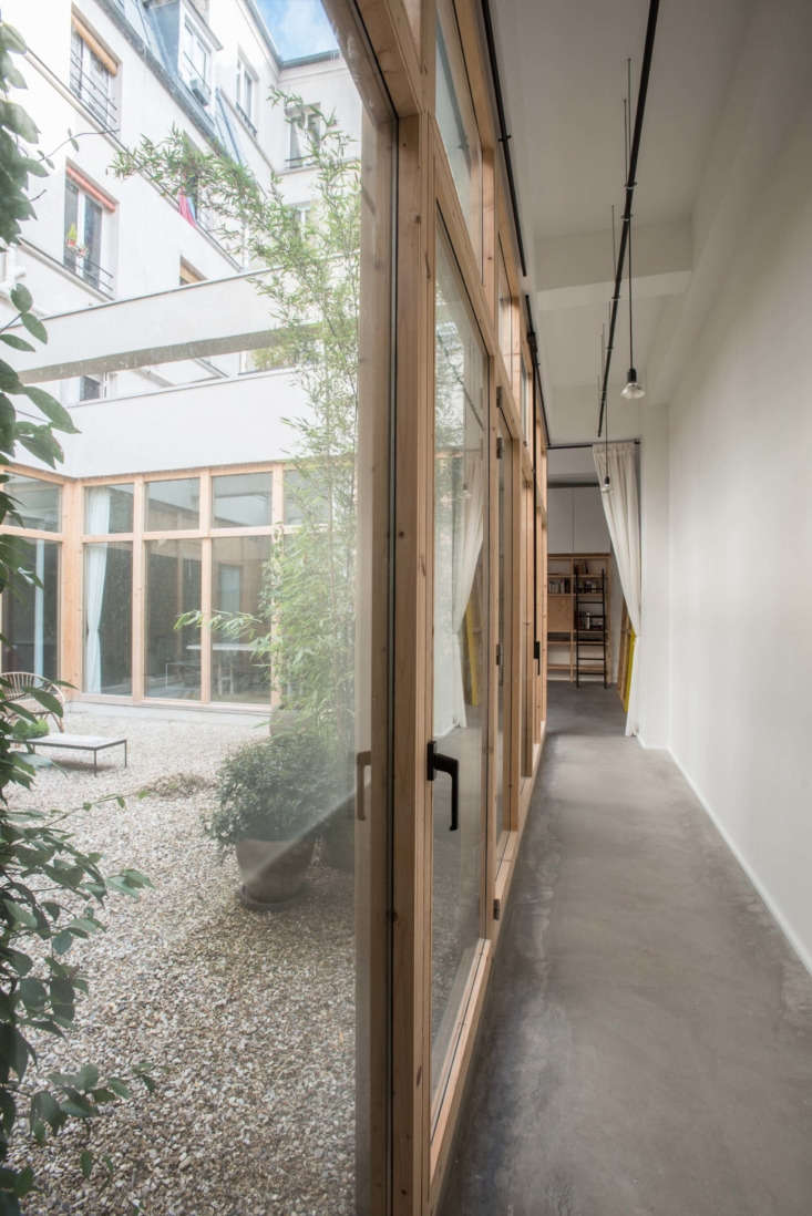 Central 387 square foot roof-free patio surrounded by glass walls and original structural beams.