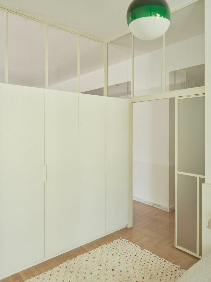 White built-in wardrobes with frosted glass panels at the top near the ceiling.